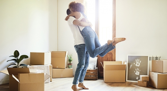 Happy couple hugging for joy with moving boxes on the floor